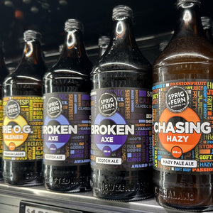 Row of 888ml  Sprig + Fern beer bottles with colorful labels on a shelf.