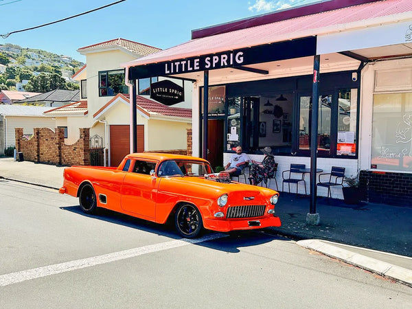 Vintage orange truck parked in front of the Little Sprig Seatoun Tavern on a sunny day.
