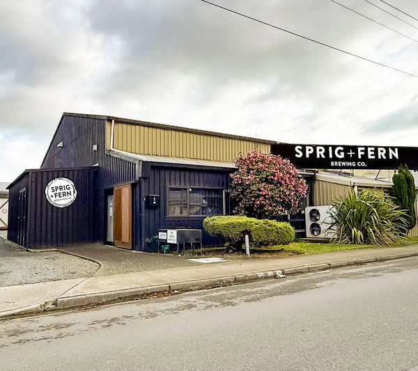 Sprig + Fern Brewing Co. brewery building with sign and surrounding greenery