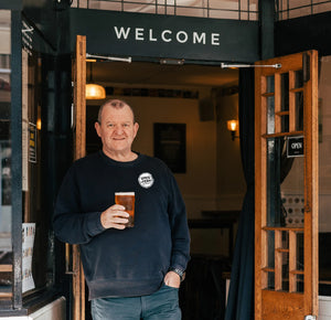 The owner of Sprig + Fern Hardy Street, Lee Fern, standing outside the tavern holding a Proper Pint of Sprig + Fern beer. 