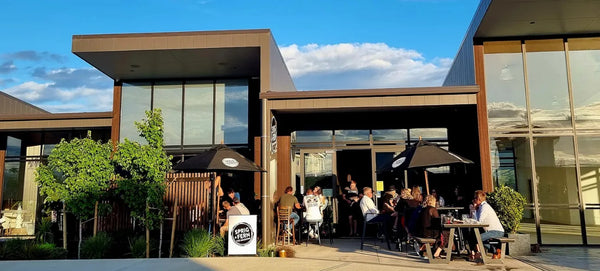 People dining outside Sprig + Fern The Meadows Tavern on a sunny day.
