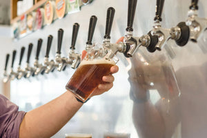 Person pouring Sprig + Fern beer from a tap into a glass.