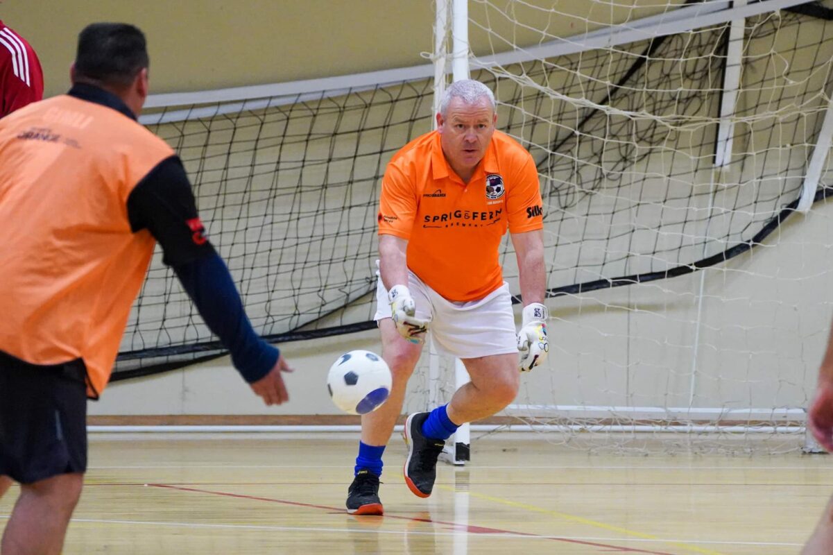 A Walking Football goal keep wearing a Sprig and Fern logo on his shirt while playing
