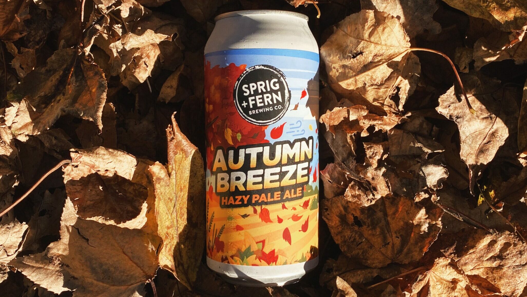 A can of Sprig and Fern Autumn Breeze Hazy laying a pile of dried leaves