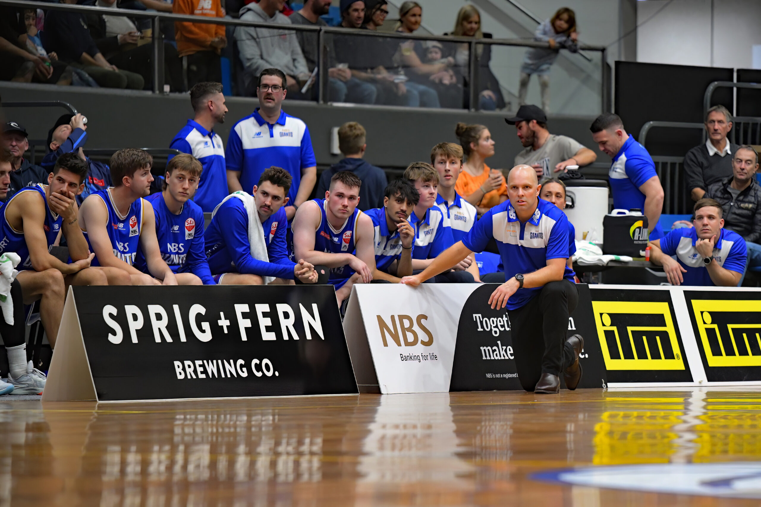 Mike Fitchett and the Nelson Giants basketball team behind a Sprig and Fern Brewing Co sign