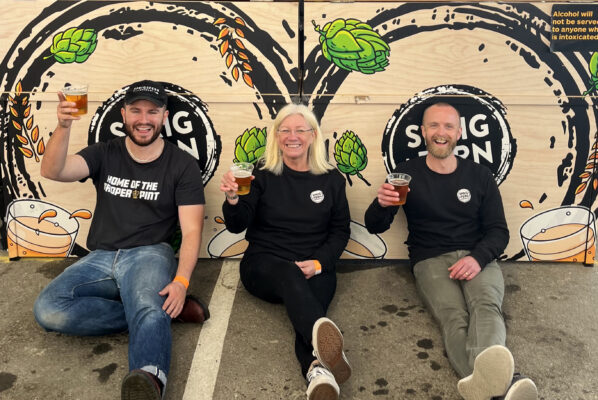 Ryan Green, Tracy Banner and Daniel Tipping of Sprig and Fern Brewing Co, sat in front of their bar at NZ Brewers Fest in Upper Hutt