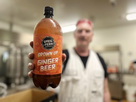 Alex from the Sprig and Fern brewing team holding a rigger of Grown Up Alcoholic Ginger Beer