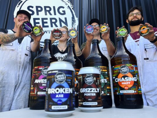 Four members of the Sprig and Fern Brewery team showcasing the new core range redesign, with a range of craft beer in the foreground