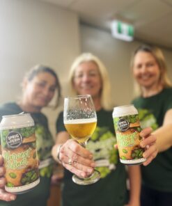 Three members of the Sprig and Fern team wearing Harvest Pilsner tee shirts and holding out cans and a glass of fresh hop Harvest Pilsner