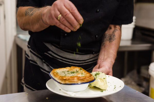 A chef sprinkling seasoning on a pie at Sprig and Fern Tawa